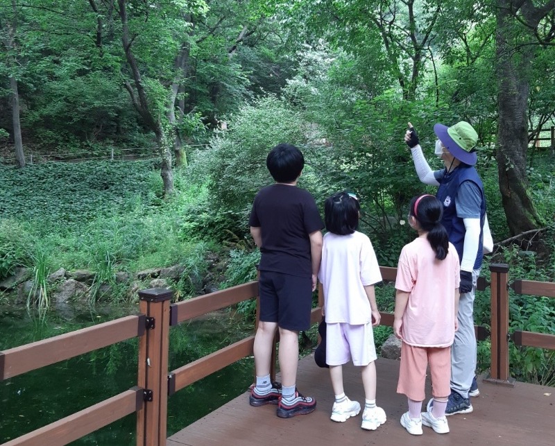 2-1. 용인자연휴양림 숲해설프로그램 참가자들이 야생화단지 산책로에서 설명을 듣고 있다..jpg