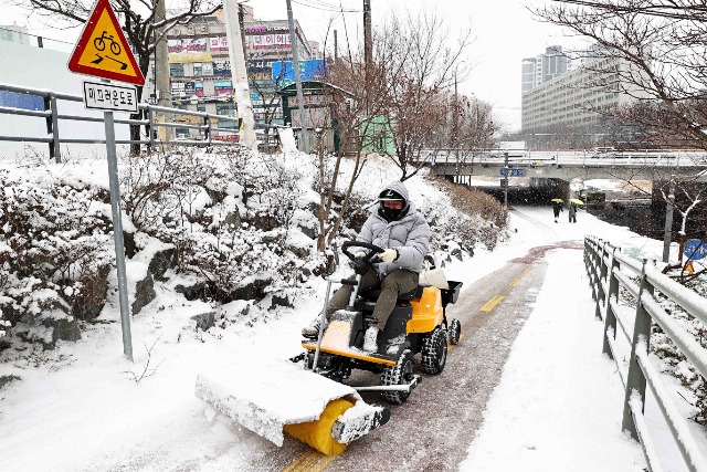 7-3. 26일 시 관계자가 수지구 성복천 산책로 비탈면에 쌓인 눈을 제설기로 치우고 있다..jpg