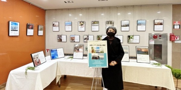 5. 용인중앙도서관서 열리는 전시장 앞에서 신혜진 시인이 기념촬영을 하고 있다.jpg