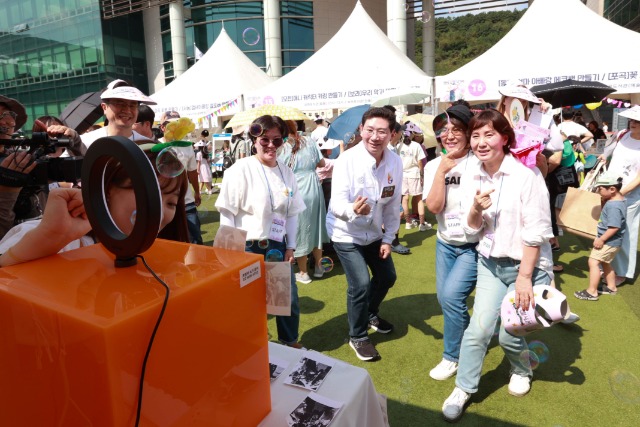 2-3. 이상일 용인특례시장이 행사장에 마련된 도서관 별 체험 부스를 방문해 도서관 직원들과 스티커 사진을 찍고 있다..JPG