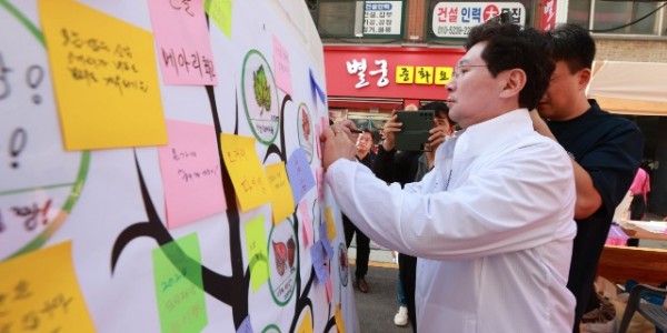 12-2. 이상일 용인특례시장이 27일 신갈오거리 거리축제에서 신갈오거리 도시재생사업의 성공을 기원하는 메세지를 작성하고 있다.JPG