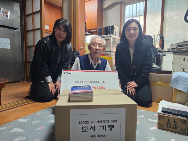 7. 16일 김상운 작가의 자택에서 김 작가가 시 도서관 관계자에게 도서를 기증하고 있다.jpg